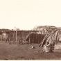 Black and white photograph of a Ho-Chunk woman sitting outside a shelter. Taken by Benjamin Franklin Upton in 1858.