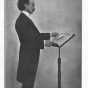 Black and white photograph of Oberhoffer at behind a podium, c.1903. 