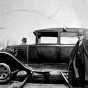 Photograph of a car straddling a railroad track. The car was used to transport Reverend John Sornberger to lumber camps c.1930.