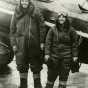 Black and white photograph of Charles and Anne Lindbergh in flight suits next to Lockheed Sirius during their flight across the Northern Pacific, c.1931.