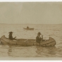 Black-and-white photograph of an Ojibwe birch bark canoe and two paddlers c.1910.