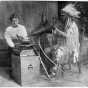 Black and white photograph of Frances Densmore with Mountain Chief who is interpreting a recording. 