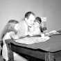 Black and white photograph of Hubert Humphrey reading comics on the radio, August 1946.