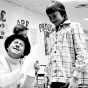 Black and white photograph of television character Roundhouse Rodney (played by Lynn Dwyer on WTCN) signing an autograph for a young fan, c.1961. 