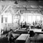 Black and white photograph showing the interior of a lumber mill, ca. 1915.