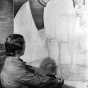 Black and white photograph of a mural in Minneapolis Armory by Elsa Jemne (seated before mural), c.1940. 