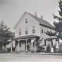 Three unidentified people in front of the Nerstrand Hotel with American flags on display, ca. 1890. Nerstrand city records, Nerstrand City Hall.