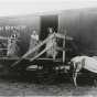 Black and white photograph of Thomas McMahon (far left), a farmer in Tara Township, loading hay onto a Great Northern Railway freight car, c.1910.