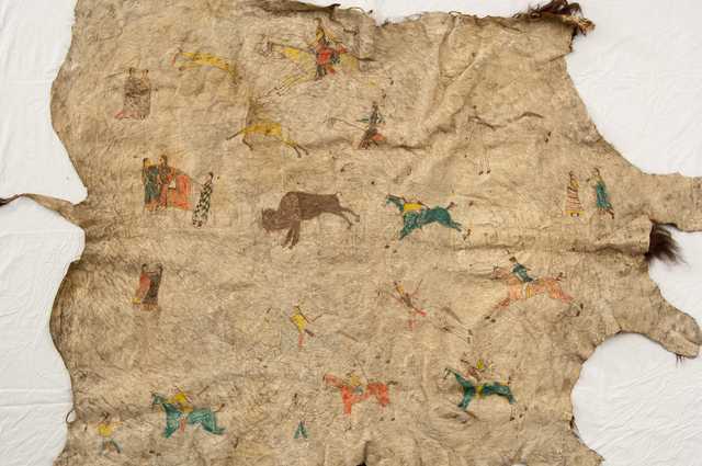 Buffalo robe painted with human figures, horses, and buffalo. Made by Dakota during the late nineteenth century.