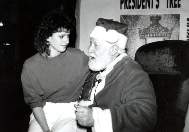 Dr. Rolland Dille, dressed as Santa Claus, with a student