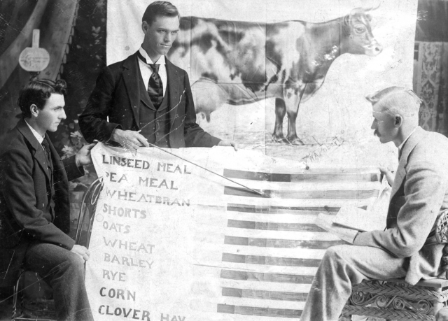 Black and white photograph of Superintendent Torger Hoverstad at a lesson about what to feed dairy cows during a Farmers Institute lecture.