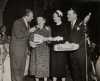 Black and white photograph from the Grand National Bake-Off at the Waldorf Astoria, New York, 1950. Left to right: Art Linkletter, contestant, Duchess of Windsor (the former Wallis Simpson), Philip Pillsbury.