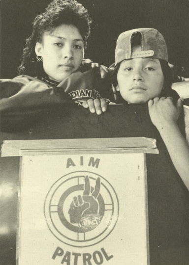 Postcard with photograph of AIM Patrol poster, 1991.