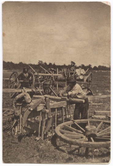 Black and white photograph of two men, probably Métis, preparing a Red River cart train at Pembina, 1856. 