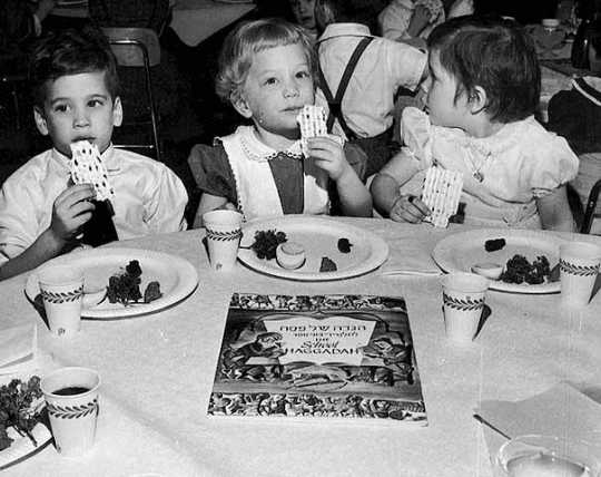 Black and white photograph of three children attending a Passover seder at the St. Paul Talmud Torah, 1960. The children are Susan Hoffman, Lisa Savitt, and Scott Zuckman.