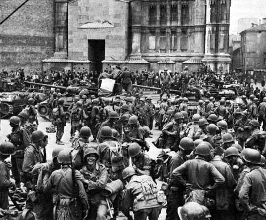 Black and white photograph of Thirty-fourth Division Infantrymen pausing to celebrate the taking of Bologna, April 1945.