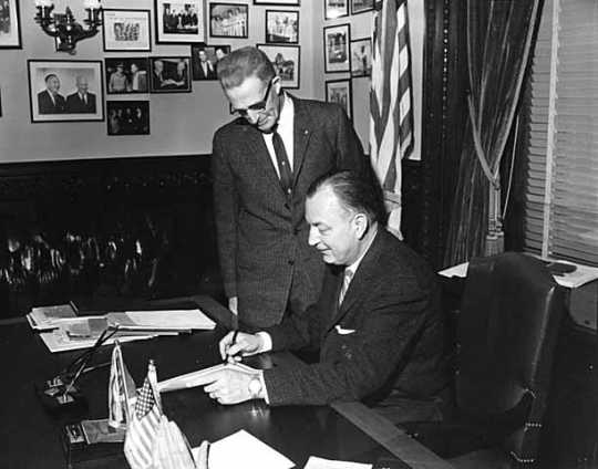 Black and white photograph of Governor Elmer Benson signing a bill with Grange Master William B. Pearson looking on, 1963. Photographed by Eugene Debs Becker. 