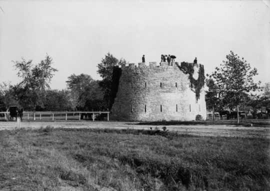 Black and white photograph of men and women with parasols standing atop the round tower, c.1900.